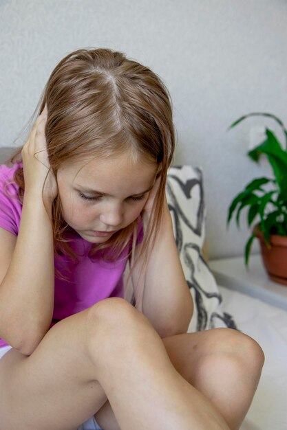 Een klein blond meisje bedekt haar oren met haar handen