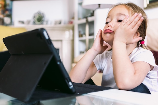 Een klein blond meisje voor een tablet gebarend tijdens het kijken naar een video concept van kindertechnologie leren met plezier internet en connectiviteit