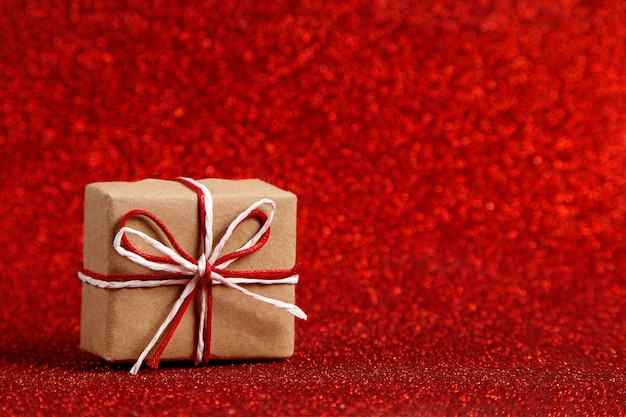 Een klein cadeautje op een rood glanzend, pailletten in de zijkant. Het concept voor Valentijnsdag.