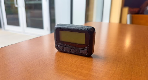 Een klein elektronisch apparaat op een tafel met een raam op de achtergrond.