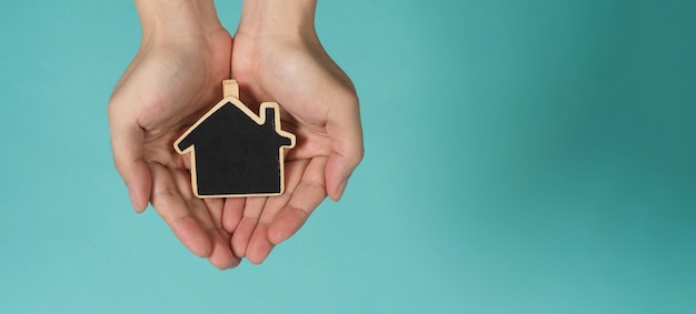 Een klein houten huis in handen vertegenwoordigt concepten zoals liefde voor thuiszorg