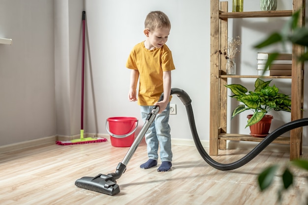 Een klein kind helpt zijn ouders in het huishouden en maakt de vloer schoon met een stofzuiger