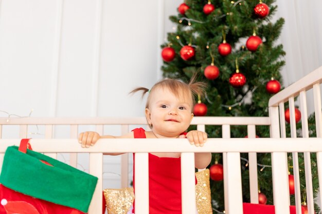 Een klein kind in bed naast een kerstboom