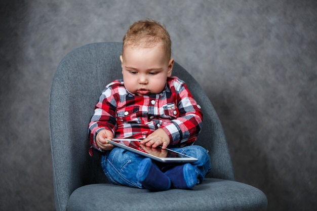 Een klein kind in een overhemd speelt met een tablet