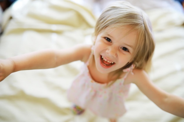 Een klein kind met blond haar ligt op het bed Babymeisje speelt op de bank