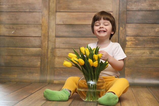 Een klein kind met een boeket gele tulpen een jongen met een geschenk van bloemen in een vaas een geschenk voor meisjes op vrouwelijke vakantie met gele tulpen op de vloerxa