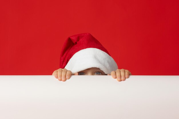 Een klein kind met een rode kerstmuts verstopte zich uit angst achter een witte vlag