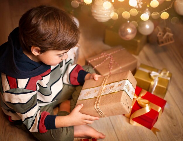 een klein kind onderzoekt cadeautjes onder de kerstboom