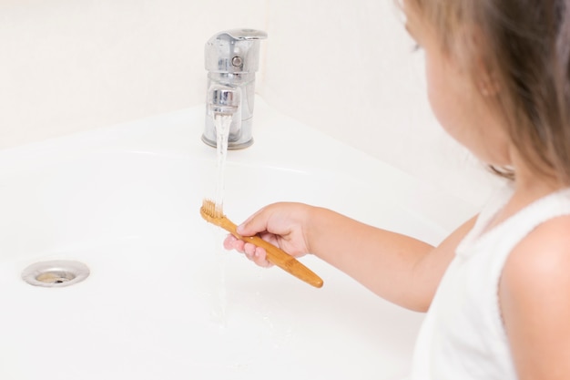 Een klein kind poetst zijn tanden met een bamboetandenborstel.