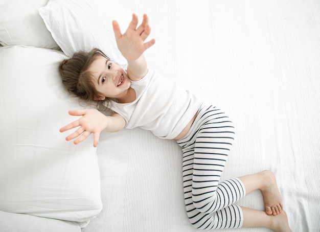 Een klein kind slaapt in een lichte pyjama op een licht bed.