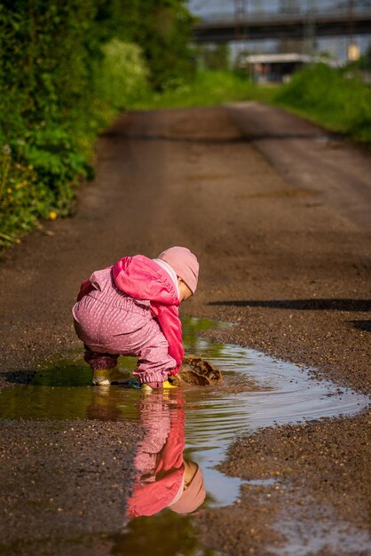 Foto een klein kind speelt in een regenpoel.