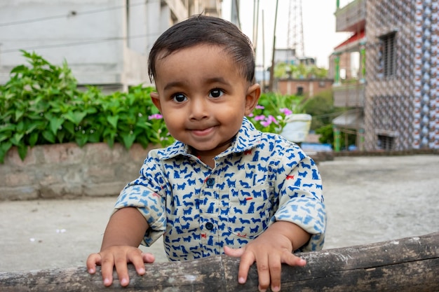 Een klein kind staat en houdt een gedroogde bamboe vast en kijkt naar de camera Baby39s smileygezicht op een mooie middag op het dak