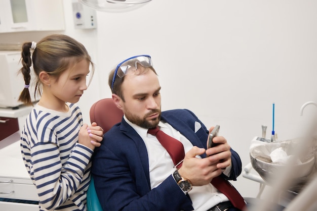 Een klein krullend meisje en haar vader spelen een gelukkige tandartsrelatie