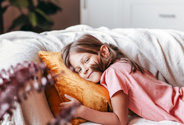 Een klein lachend meisje ligt op de bank. Gelukkige jeugd. Rust voor kinderen