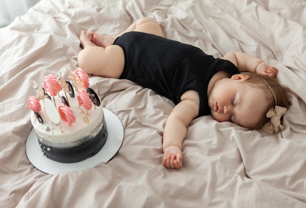 Een klein lief babymeisje slaapt schattig op het bed met cake Verjaardag