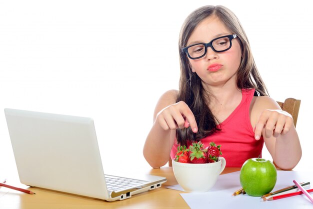 Een klein meisje aan haar bureau kijkt naar zijn snack