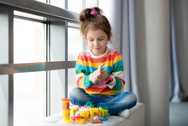 Een klein meisje beeldhouwt uit plasticine