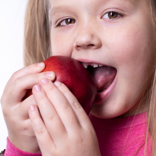 Een klein meisje bijt een rode grote appel