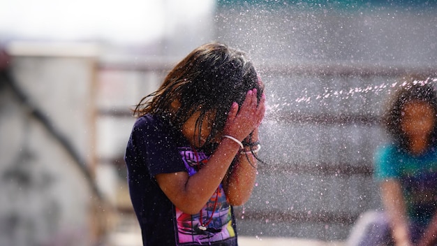 Een klein meisje dat met water speelt met het beeld van haar vrienden