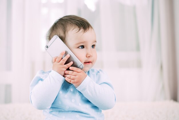 Een klein meisje dat op een smartphone praat, glimlachend en blij heel lief