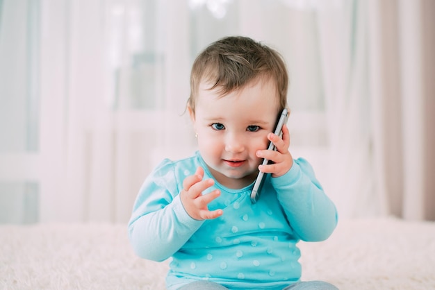 Een klein meisje dat op een smartphone praat, glimlachend en blij heel lief