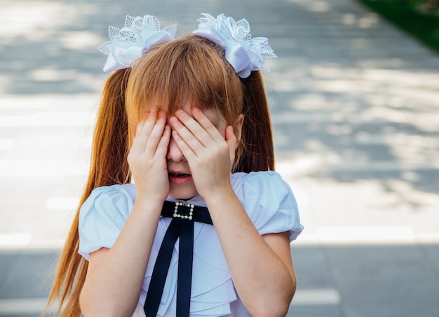 Een klein meisje, een leerling van een basisschool, staat op straat.