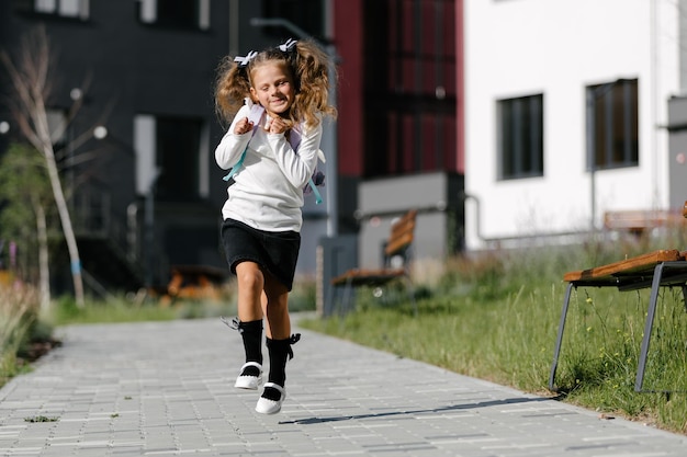 Een klein meisje gaat door het park langs het pad naar school. afstandsonderwijs concept. schoolmeisje