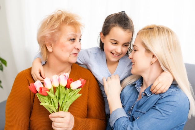 Een klein meisje geeft een boeket tulpen aan haar moeder en grootmoeder. Ze vieren Moederdag. Ze hebben een traditionele familievakantie.