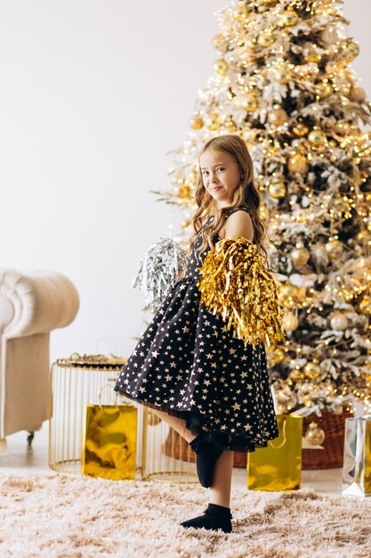 Een klein meisje hangt kerstspeeltjes op de kerstboom.