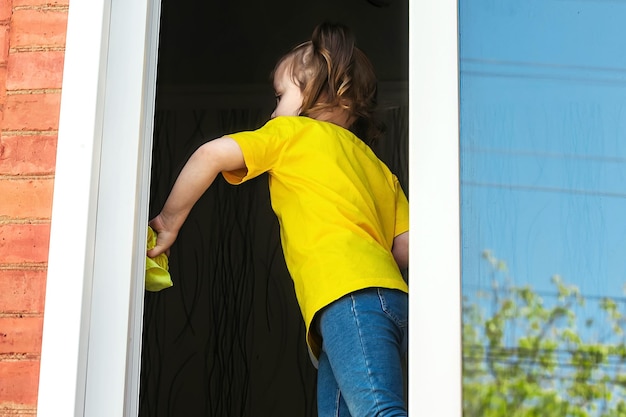 een klein meisje helpt haar moeder in huis, ze wast het raam