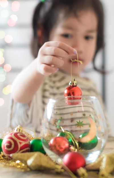 Een klein meisje houdt een kerstbal in haar hand.