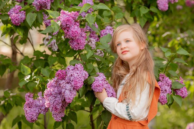 Een klein meisje houdt lila bloemen vast in een lila tuin in de lente