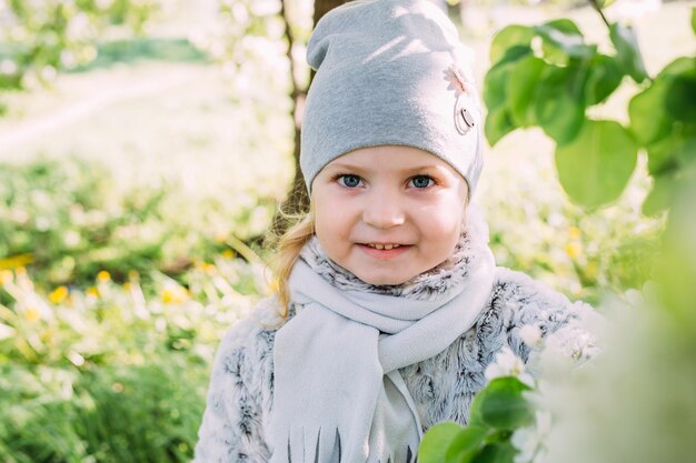 Een klein meisje in de natuur bewondert de witte bloei van lentebomen