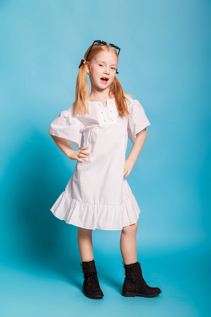 Een klein meisje in de witte jurk en zwarte schoenen