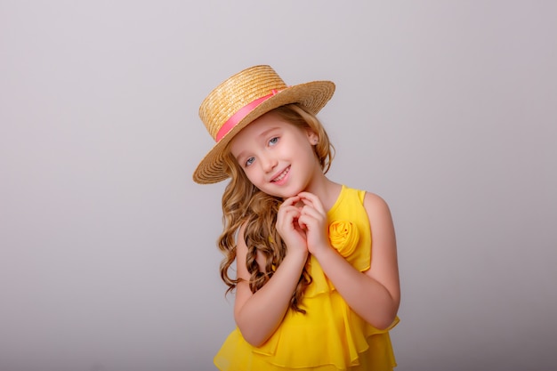 een klein meisje in een gele jurk en een strooien hoed