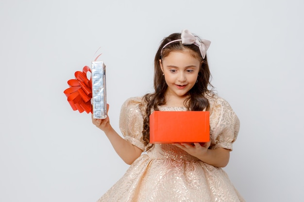 Een klein meisje in een mooie jurk houdt een geschenkdoos vast op een witte achtergrond