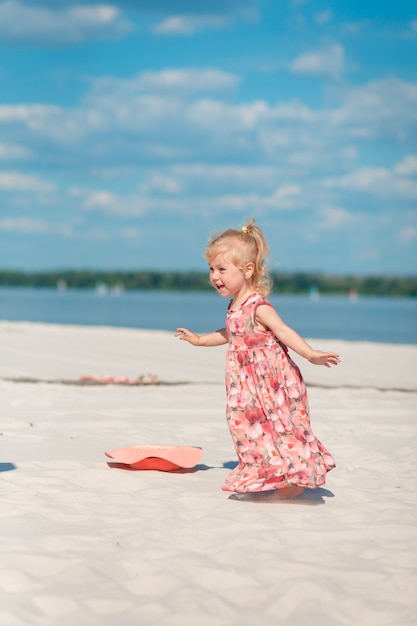 Een klein meisje in een prachtige sarafna speelt in het zand op het strand.