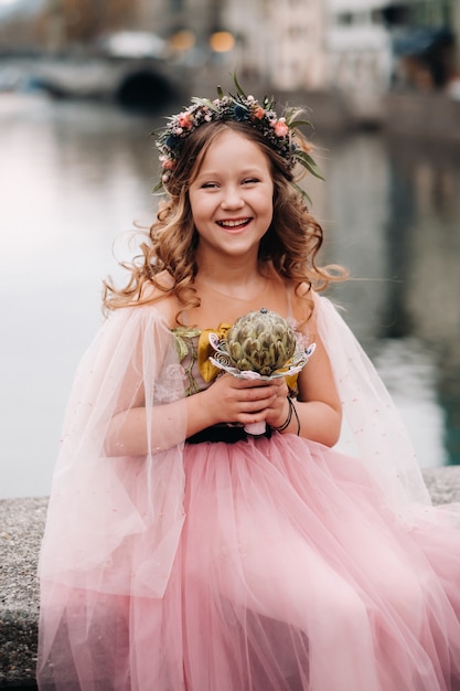 Een klein meisje in een roze prinsessenjurk met een boeket in haar handen loopt door de oude stad zürich.