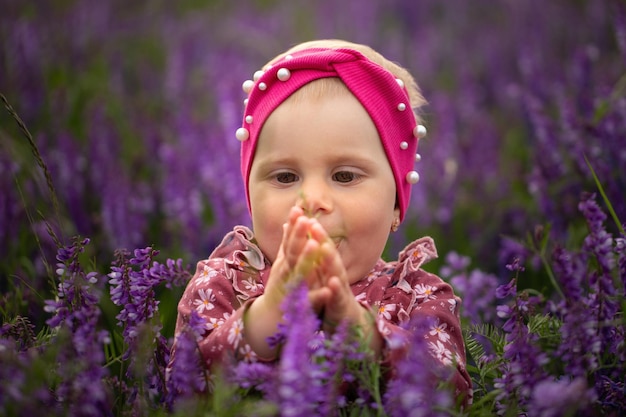 Een klein meisje in een veld met paarse bloemen