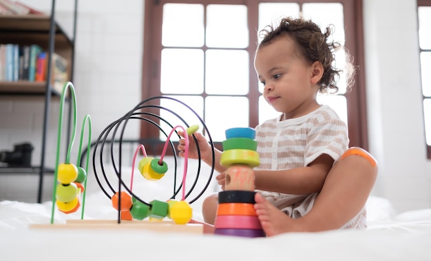 Een klein meisje in zijn slaapkamer met een nieuw speelgoed dat zijn ouders hebben gekocht om hem te helpen zijn denken te verbeteren