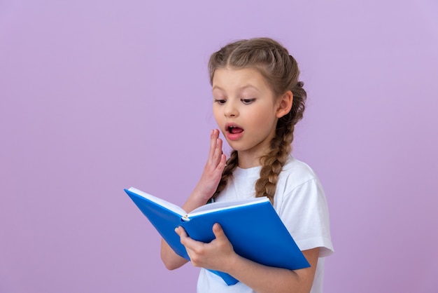 Een klein meisje is zeer verrast om een interessant boek te lezen.