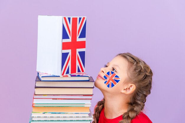 Een klein meisje kijkt naar een grote opgevouwen stapel boeken over de Engelse taal.