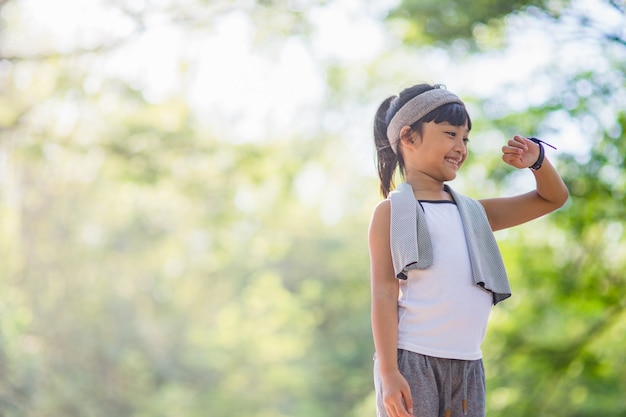 een klein meisje kijkt naar een slim horloge na een training in het park. gezond begrip. vrouw na