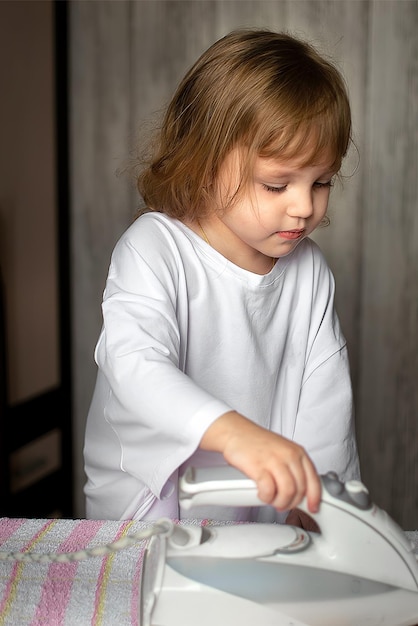 een klein meisje kopieert volwassenen ze strijkt kleren als een kleine helper