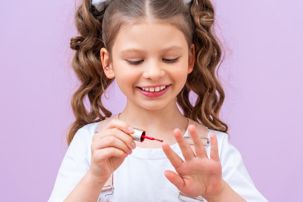 Een klein meisje lakt haar nagels met nagellak Een mooi meisje doet nagellak op haar nagels