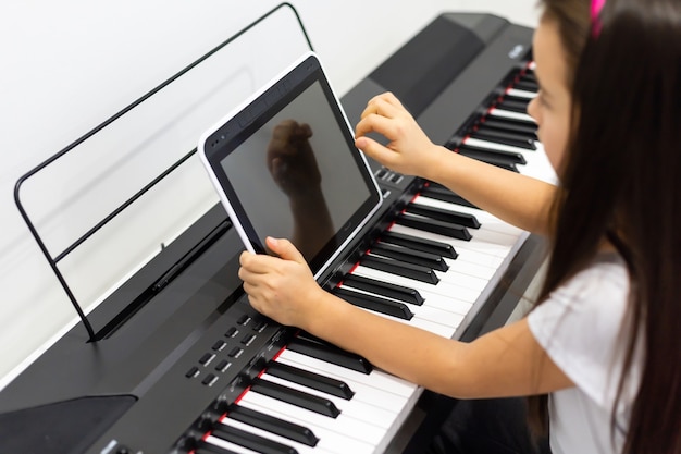 Een klein meisje leert piano spelen via videolessen. online afstandsonderwijs tijdens covid-19