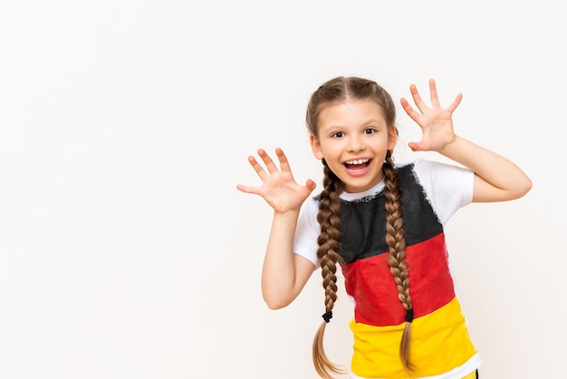 Een klein meisje met een Duitse vlag op een T-shirt met lang haar gevlochten in staartjes op een witte geïsoleerde achtergrond Taalcursussen voor kinderen Ruimte kopiëren