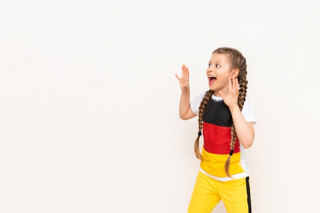 Een klein meisje met een Duitse vlag op een T-shirt met lang haar gevlochten in staartjes op een witte geïsoleerde achtergrond Taalcursussen voor kinderen Ruimte kopiëren