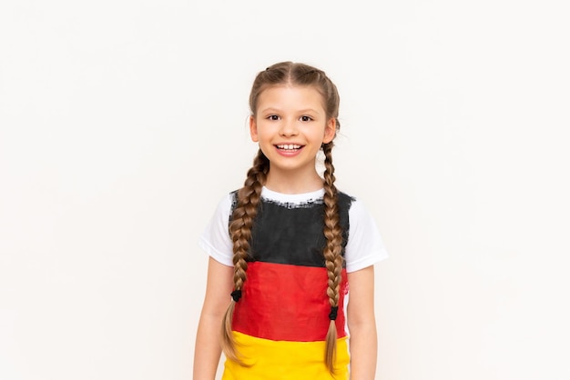 Een klein meisje met een Duitse vlag op een T-shirt met lang haar gevlochten in staartjes op een witte geïsoleerde achtergrond Taalcursussen voor kinderen Ruimte om te kopiëren