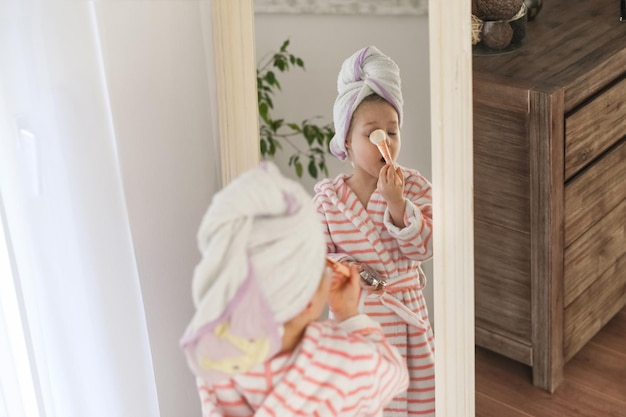 Een klein meisje met een handdoek op haar hoofd die make-up doet.